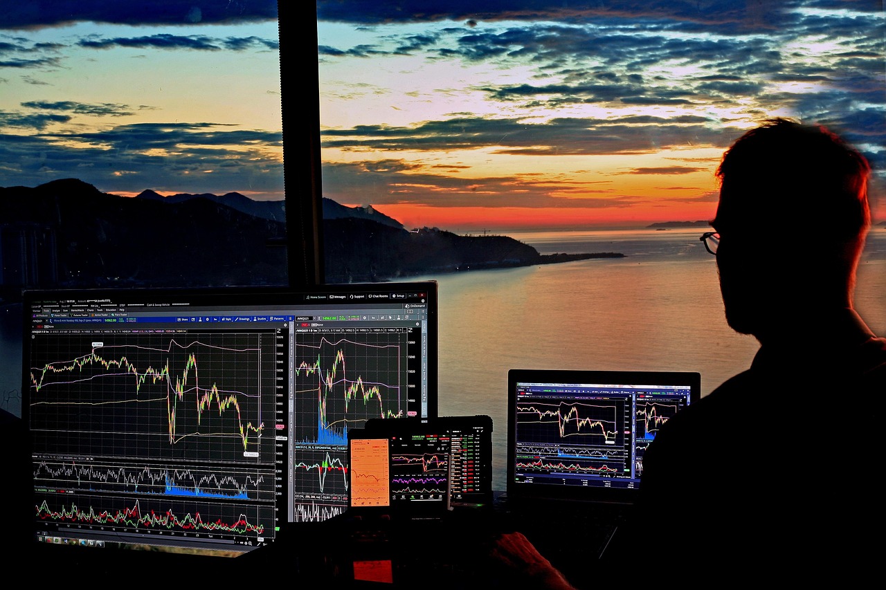 Pantallas con gráficos de cotizaciones al atardecer: backtesting en trading con datos históricos